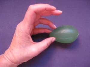 A hand using an Eggsercizer to improve grip strength